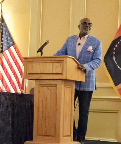 Speaker at a podium with U.S. flag and state flag