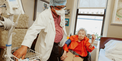 Medical staff assisting an elderly resident in a care room