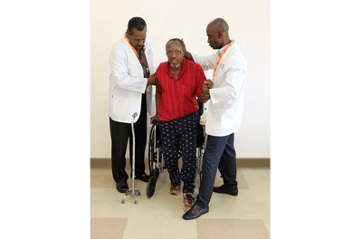 Two staff members assisting a resident in a wheelchair.