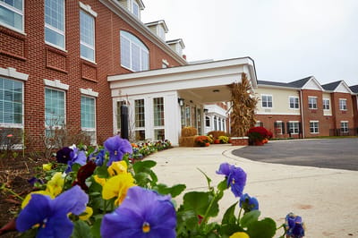 Exterior view of a senior living facility entrance with flowers