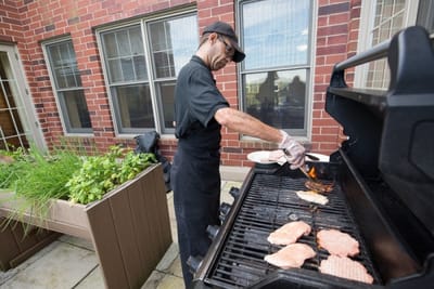 Staff member grilling food in an outdoor area