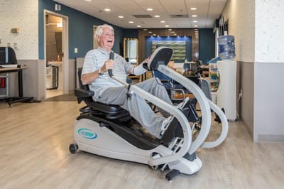 Senior man exercising on a fitness machine in a well-lit room