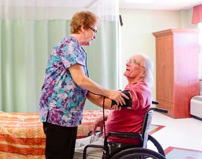 Healthcare staff assisting a resident in a room