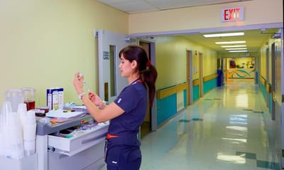 Staff member preparing medication in a bright hallway