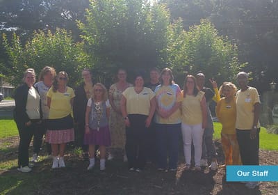 Staff members posing together outside in matching shirts
