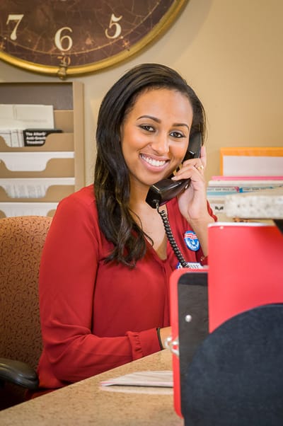 Staff member smiling at the front desk on the phone