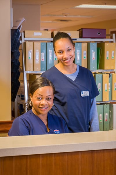 Two staff members smiling at the reception desk
