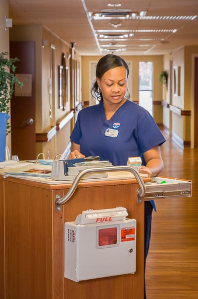 Nurse attending to paperwork in a facility hallway