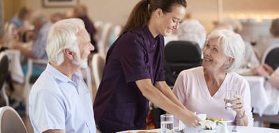 Staff serving food to residents in a dining room