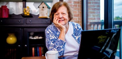 A resident smiling while using a laptop in a cozy interior