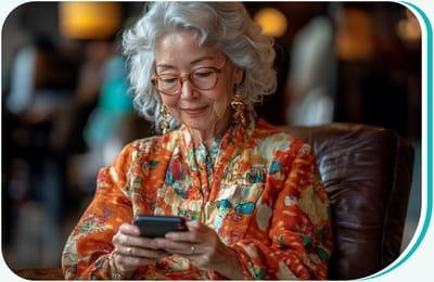 An older woman in colorful attire using a smartphone in a cozy common area