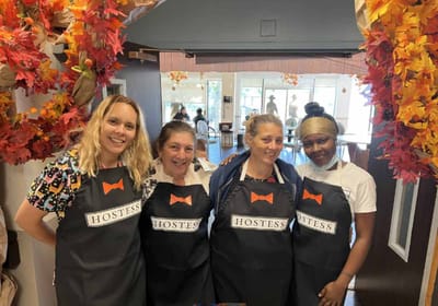 Staff members in aprons welcoming guests