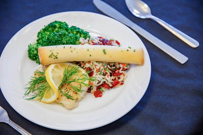 A plated meal featuring fish, rice, and broccoli