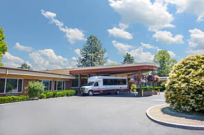 Exterior view of the facility entrance with a shuttle bus