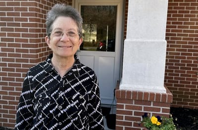 Resident smiling in front of the facility entrance