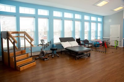 Rehabilitation gym with exercise equipment and large windows