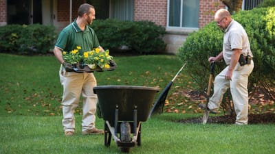 Two staff members gardening outside in a green space