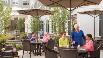 Residents enjoying time outdoors at tables under umbrellas