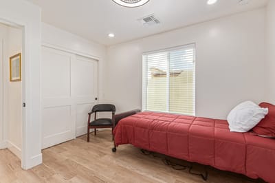A private resident room with a red bed and chair