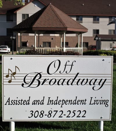 Sign for Off Broadway Apartments in front of a building