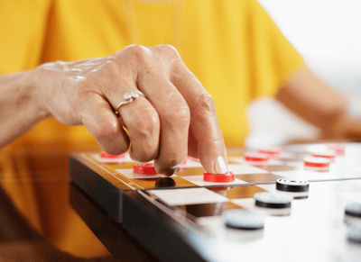 Close-up of a hand playing checkers on a wooden board