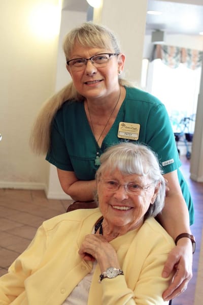 A staff member posing with a resident in a common area