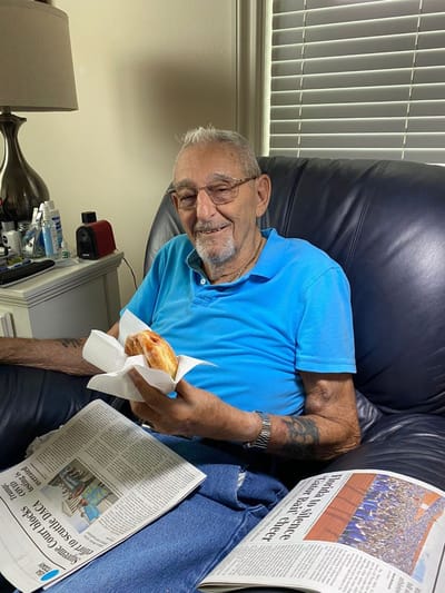 Resident enjoying a meal while reading a newspaper