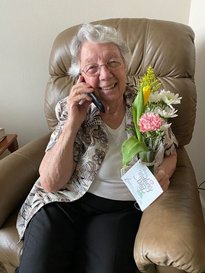 Senior resident joyfully talking on the phone with flowers