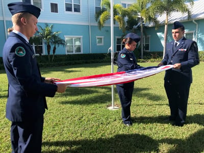 Three cadets folding the American flag during a ceremony