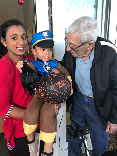 A caregiver with a child in a costume and an elderly resident