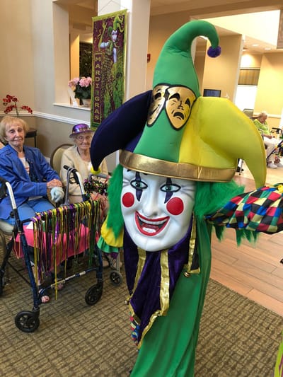 Residents enjoying Mardi Gras festivities with a jester performer