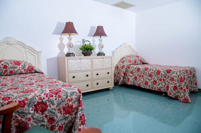 A shared resident room with floral bedding and lamps