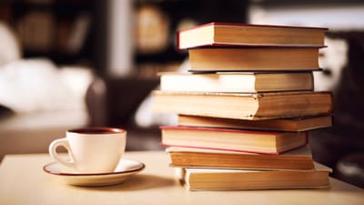 A stack of books with a coffee cup in a cozy setting