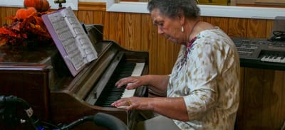 Resident playing piano in a cozy activity room