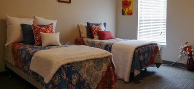 Cozy resident room with two beds and decorative pillows