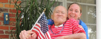 Patrick Manor, Inc., assisted living in Saint Petersburg, FL — Senior resident holding an American flag with caregiver