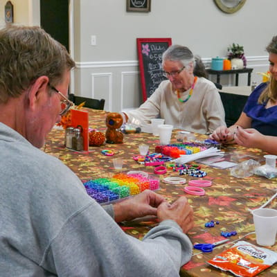 Residents crafting with colorful beads at a table