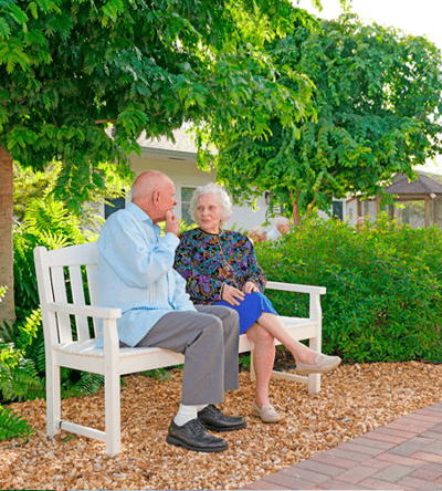 Two residents sitting on a bench in a garden