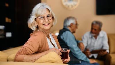 A smiling resident enjoying tea in a common area.