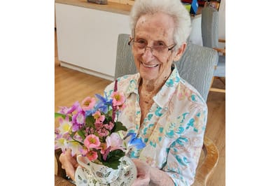 Resident smiling while holding a flower arrangement