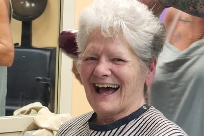 Resident smiling during a hair appointment