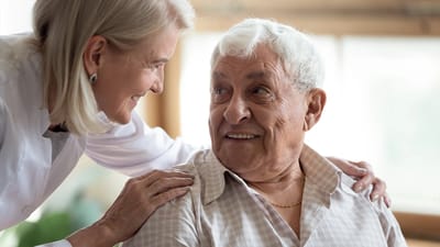 Caregiver smiling at a resident in an interior setting