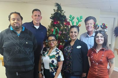 Staff and residents posing in front of a holiday tree