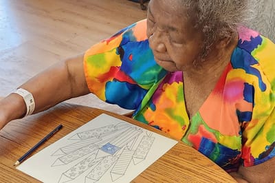 Resident coloring at a table in a communal area