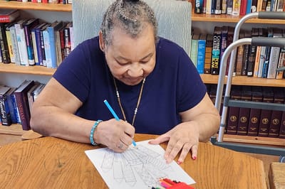 Resident coloring at a table in an activity room