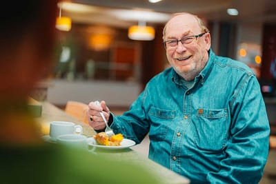 Resident enjoying a meal in a facility dining area