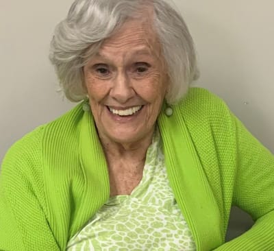 A smiling elderly woman in a green sweater