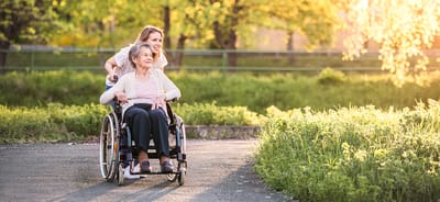 Woman pushing a resident in a wheelchair in a park