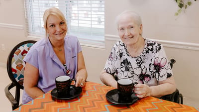 Resident and staff enjoying refreshments at a table