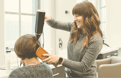Stylist using a hairdryer on a resident's hair